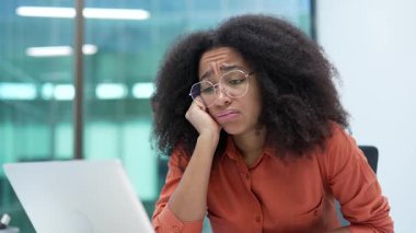 Afrikalı Amerikalı iş kadını iş yerinde oturmaktan sıkıldı. Üzgün, bitkin kadın çalışan bir dizüstü bilgisayarla çalışmaktan yoruldu. Tembel işçi oyalanıyor, dikkati dağılıyor. Kapat.