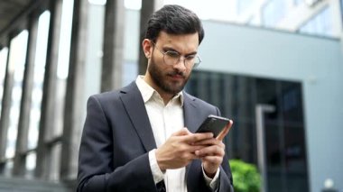 Ciddi odaklı iş adamı, ofis binasının yanındaki caddede duran bir cep telefonu kullanıyor. Resmi takım elbiseli kendine güvenen girişimci e-postaları kontrol ediyor, internette sohbet ediyor, iş ortağına mesaj atıyor. Kapat.
