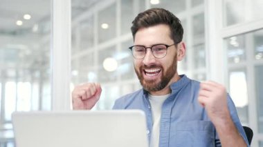 Mutlu iş adamı, modern iş ofisindeki iş yerinde dizüstü bilgisayarında harika haberler aldı. Gülümseyen şaşkın girişimci olumlu iyi bir mesaj okuyor, başarıyı kutluyor. Kapat.