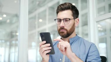 İş yerindeki akıllı cep telefonunda çalışan yazılımla ya da servisle ilgili sorunları olan endişeli iş adamı. Hayal kırıklığına uğramış çalışan kötü internet bağlantısından şikayetçi