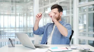 Mutlu iş adamı, modern bir iş ofisindeki çalışma masasında otururken dizüstü bilgisayardaki işini bitirdi. Gülümseyen tatmin olmuş bir adam ellerini başının arkasına koyar ve kendini sandalyeye yaslar. İş tamam.