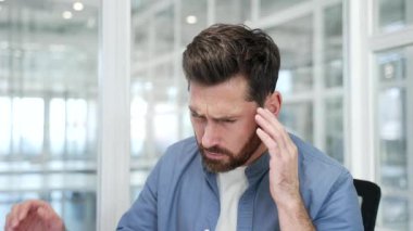 İş yerinde çalışırken baş ağrısı çeken bir iş adamı. Elleriyle şakaklarını tutup masaj yapan üzgün bir işçi. Çok yorgun ve yüksek tansiyonu var. Kapat.