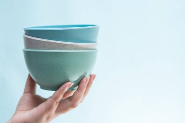 Elinde parlak mavi arka planda mavi seramik saksıları var.