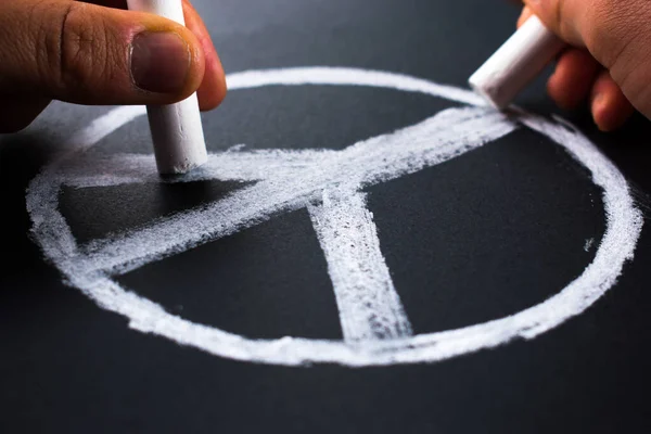 stock image Hands drawing peace symbol with white chalks on blackboard