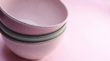 Pembe arka planda pembe seramik saksıları alan bir el.