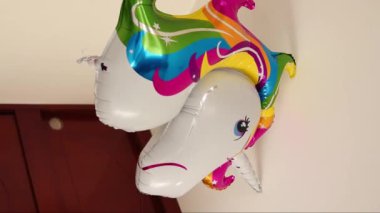 Odaya renkli bir tek boynuzlu at balonu alırken çekilmiş dikey bir video.
