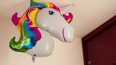 Elin rengarenk bir tek boynuzlu at balonunu odaya alıyor.