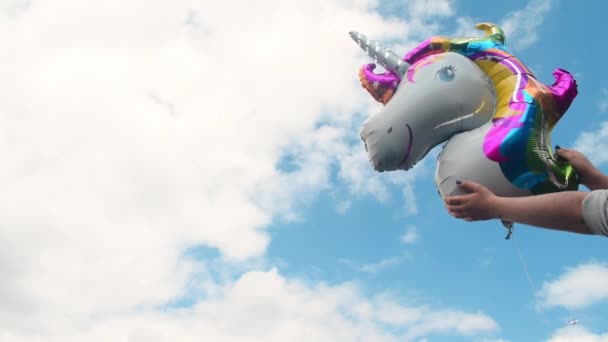 Arka Planda Bulutlu Gökyüzünde Renkli Bir Tek Boynuzlu Balonu Tutan — Stok video
