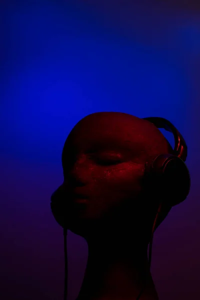 Over-ear headphones on black head on blue and red background