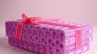 Hand taking a gift box on pink background