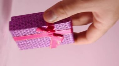 Vertical video of hand taking a gift box on pink background