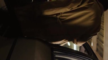 Vertical video of man getting into the car and starting it in the parking lot