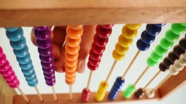 Vertical video of a hand working with a colorful wooden abacus on green background