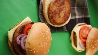 Sebzeli, ekmeksiz ve taze burgerli taze hamburgerlerin bir tanesini çekerken çekilmiş dikey videosu.