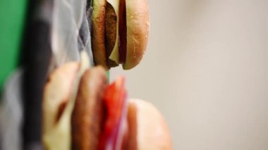 Sebzeli, ekmeksiz ve taze burgerli taze hamburgerlerin bir tanesini çekerken çekilmiş dikey videosu.