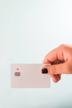 Elinde kredi kartı tutan siyah tırnaklı bir el.