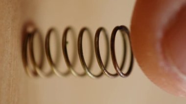 Dikey video, ahşap yüzeyde metal bir yay alıyor.