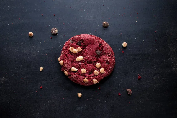 Red chocolate cookie with chips on black table