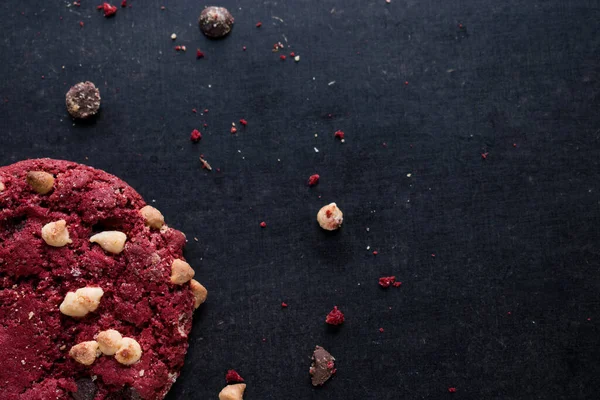 Red chocolate cookie with chips on black table