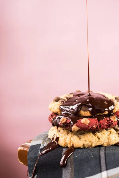 Chocolate sauce falling on red chocolate cookies