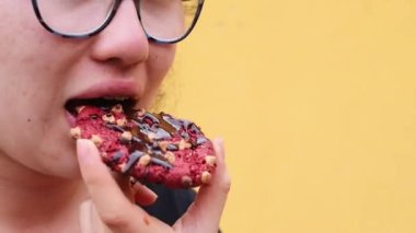 Çikolata soslu kırmızı çikolatalı kurabiyeyi ısıran kız.