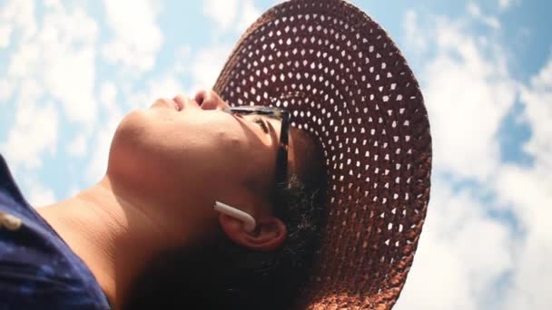 Pionowe Nagranie Kobiety Wiklinowym Kapeluszu Zdejmującej Słuchawkę Słoneczny Dzień — Wideo stockowe