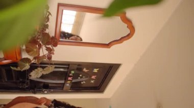 Evden çıkarken mavi elbiseli bir kadının hasır şapka giydiği dikey bir video.