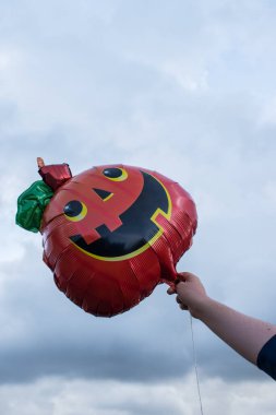 Bulutlu bir günde elinde balon tutan bir kadın.