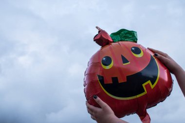 Bulutlu bir günde elinde balon tutan bir kadın.