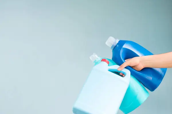 青い背景に青い液体石鹸のボトルを握る手 — ストック写真
