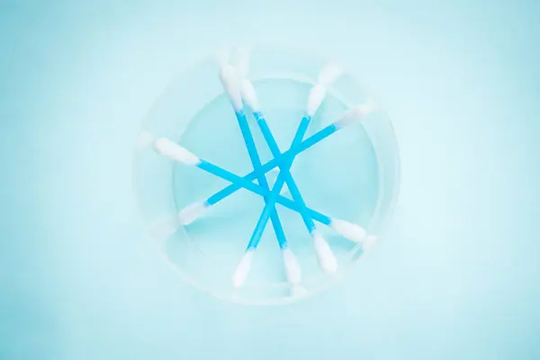 Top view of plastic blue cotton swabs container on blue background