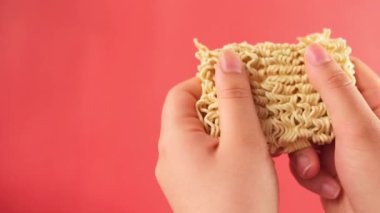 Eller kırmızı arkaplanda fotokopi alanı ile hazır erişteleri eziyor