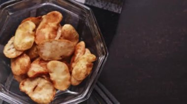 Siyah arka planda cam tencereden tost alan bir adamın dikey videosu.