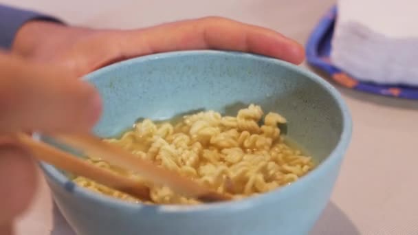 ダイニングルームテーブルの鍋からインスタント麺を食べる男 — ストック動画