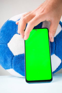 Futbol topunun yanında yeşil ekranlı akıllı telefon.