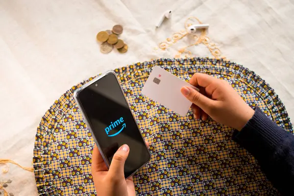 Woman holding credit card and amazon prime logo on smartphone screen