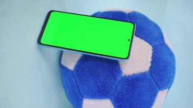 Futbol topunun yanındaki yeşil ekranlı akıllı telefonu alan el videosu