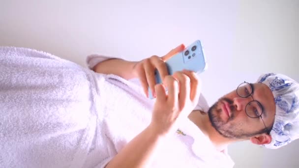 Vídeo Vertical Homem Vestindo Toalha Touca Banho Olhando Smartphone Azul — Vídeo de Stock