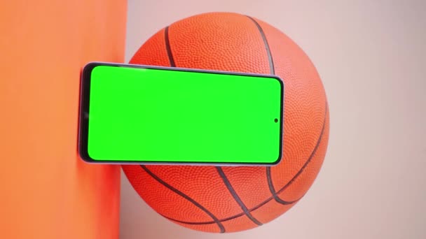 Vertikální Video Rukou Chytrým Telefonem Zelenou Obrazovkou Vedle Oranžového Basketbalu — Stock video