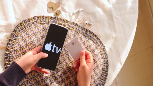クレジットカードを持っている女性と画面上のリンゴのテレビのロゴでスマートフォンを残す — ストック動画
