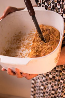 Önlük takan ve ekmek parçasında bıçak tutan bir kadın.