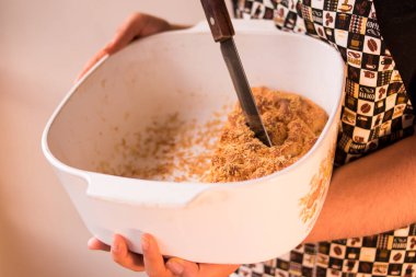 Önlük takan ve ekmek parçasında bıçak tutan bir kadın. 