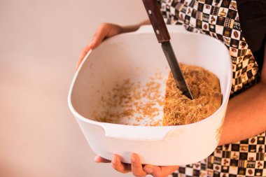 Önlük takan ve ekmek parçasında bıçak tutan bir kadın. 