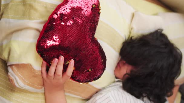 赤い心のクッションでベッドに横たわっている女性の垂直ビデオ — ストック動画