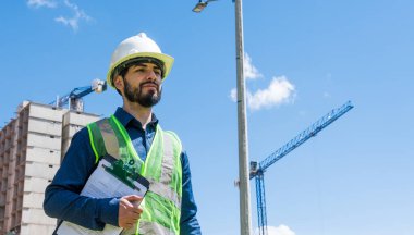 İnşaat işçisi portresi, güneşli bir günde şantiyede.