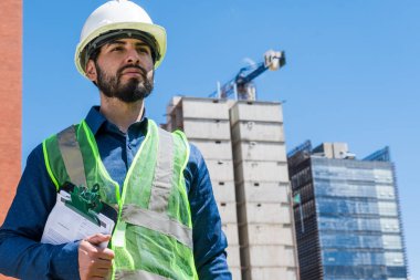 İnşaat işçisi portresi, güneşli bir günde şantiyede.
