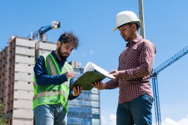 İş yerindeki işçiler inşaat sahasında anlaşma için bazı belgeleri imzalıyorlar