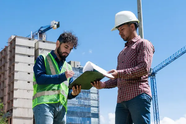İş yerindeki işçiler inşaat sahasında anlaşma için bazı belgeleri imzalıyorlar
