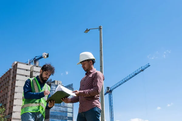 İş yerindeki işçiler inşaat sahasında anlaşma için bazı belgeleri imzalıyorlar