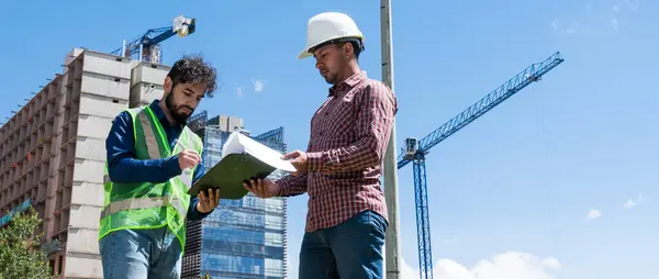 İş yerindeki işçiler inşaat sahasında anlaşma için bazı belgeleri imzalıyorlar